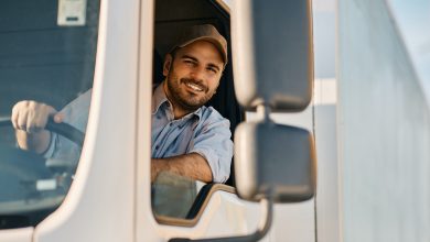 Happy truck driver looking through side window while driving his truck.