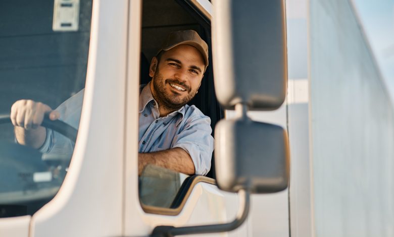 Happy truck driver looking through side window while driving his truck.