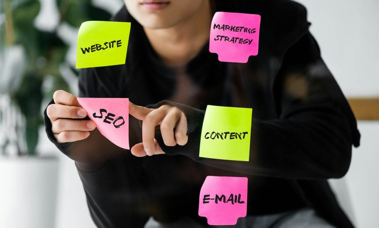 cropped view of seo manager sticking paper with seo illustration on glass